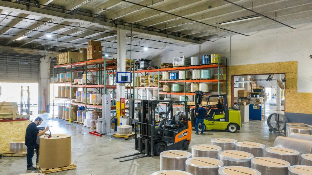 Stacks of industrial timber pallets organized in a high-density Sydney warehouse with forklifts in the background